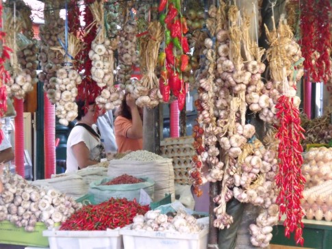 Colourful strings of garlic and chillies in an open market stall.