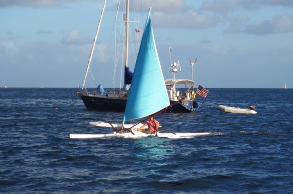 A canoe with two outriggers and a sail.