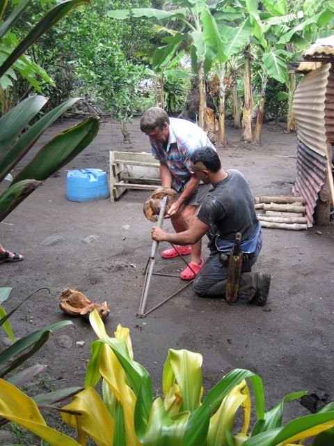 Tia shows Andy  how to de- husk a coconut