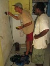 Jim fixing the solar/battery wiring at Loltong Dispensary while nurse Philip looks on with great hope