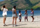 Beth & Linds chat with kids on the beach.  Their shirts are full of mangoes!