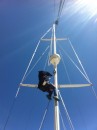 Cheryl up the mast getting down the line that controls the spinnaker pole.
