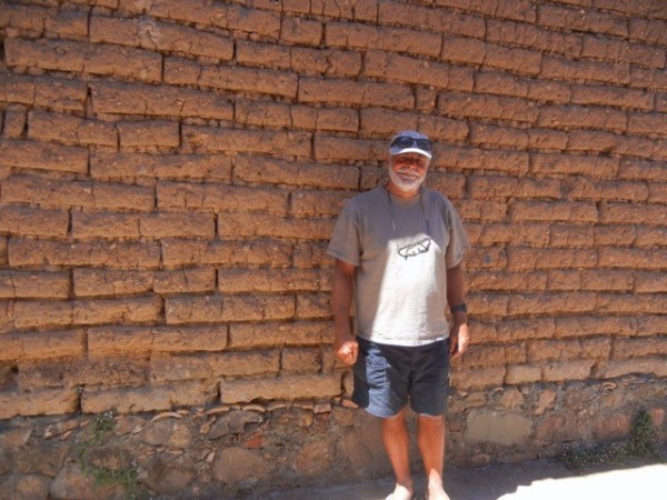 Ian in front of adobe brick wall.