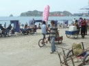 Fairy floss (cotton candy) for sale on the beach at Santa Marta on a festive Sunday.  People are sitting under the blue shelters on the beach.