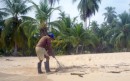 Munoz sweeping the beach on his coconut plantation island in Panama
