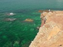 Young boys jumping from the cliff tops down into the beautiful green water near the Portara.