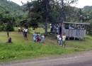 Children in uniform waited at wooden shelters for their school bus to arrive
