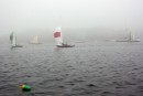  A racing fleet of keelboats emerged and disappeared one by one in the mist