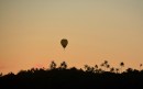 Hot air balloon descending at sunset on a nearby island
