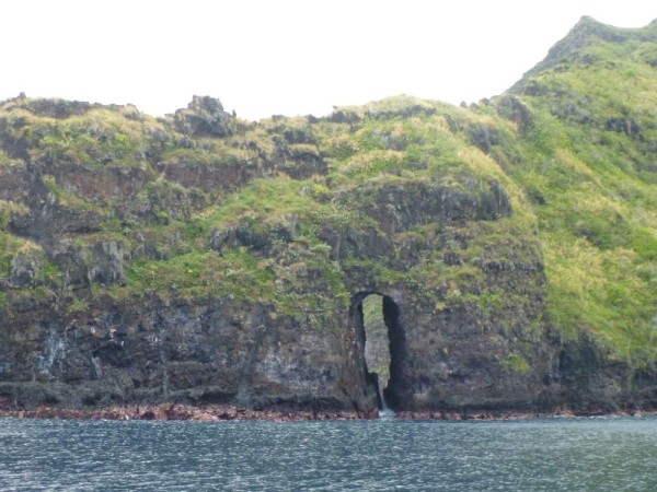 The coast of Fatu Hiva is rugged,  here a tunnel has been eroded through the lava wall.
