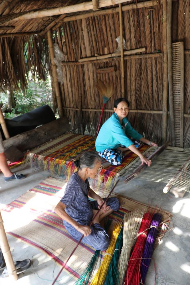 Mother and daughter weaving sleeping mats from locally grown reeds.  Each mat is approximately 4 ft by 6 ft.  It takes them 4 hours to make each mat,  which are sold to a trader who then takes them to the city to sell.  The ladies have to buy the reeds from a local grower, and after material costs their profit is $2 per mat.   That works out to 25 cents per hour per person!!