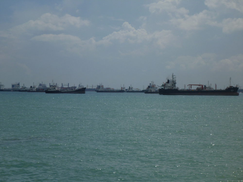 The Singapore Straights,  the sea lanes  between Indonesia,  6 miles away,  the country are the most heavily trafficked shipping lanes in the world.  More than 70,000 cargo ships per year pass through this area.  These are a few anchored offshore waiting to lad or offload cargo.