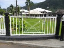 Decoative wrought iron fences enclose the front portion of the Fono (American Samoan legislature) lawn. The emblems in the center of this wrought iron panel represent a fly whisk, club, and drum symbols of the high chief, or matai.