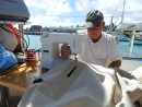 Capt. Jim mends our ripped bimini top on a sewing machine in the cockpit.