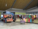 Booths with colorful clothing and souvenirs are set up in the central open air section of the cultural center.