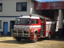 A firetruck sits at the ready at the fire station.