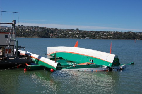 The French Trimaran that capsized off the coast of Dunedin gets towed in, still upside down
