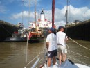 Canal Transit – Gene and Glenn pulling in the slack as we rise in the Pedro Miguel lock. In front of us is a tug, the Atlantide, and a large ship. 