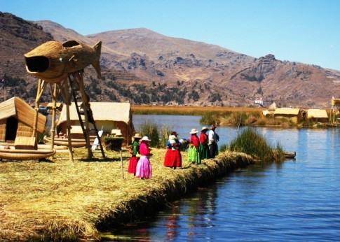 Islas Flotantes on Lake Titicaca. Good view of the reed islands, houses and watchtower. Local Uros women await a boat of tourists. 
