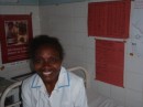 Midwife at Lamap clinic (orange tables on wall behind her are local census data)