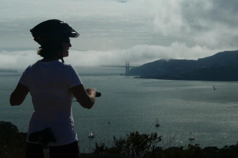 Beth pauses riding to take in the view of the Golden Gate, mostly hidden in fog.