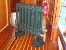 The small cast iron radiator with the wooden blocks I made to help keep it in place, they even ended up level! You can see the oldfashioned brass valves also.