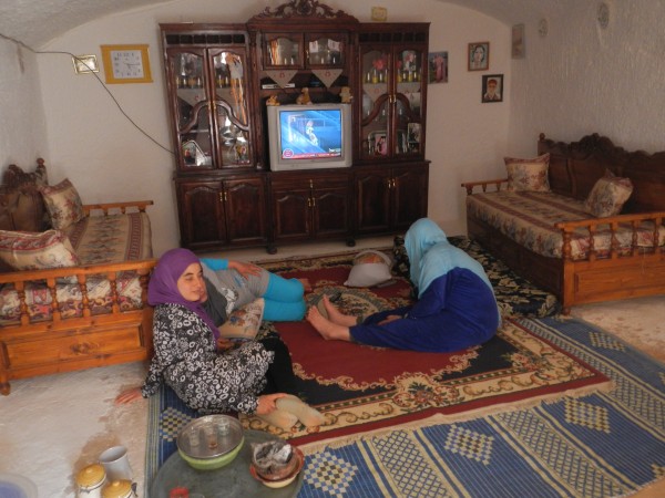 Berber women watching TV by satellite in their mountain cave dwelling 