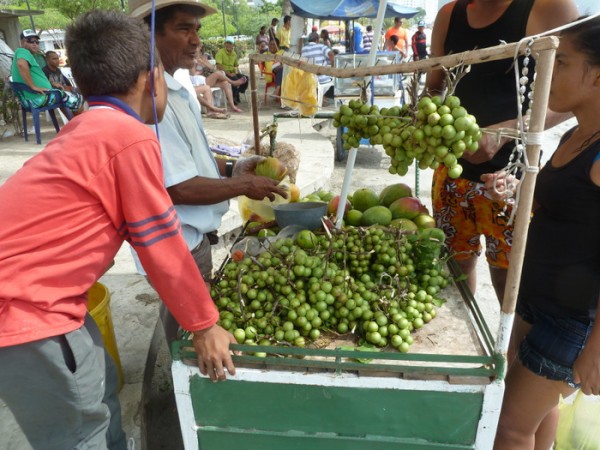 Street sellers offer sliced mangoes and fruit drinks alongside the beach at Santa Marta.