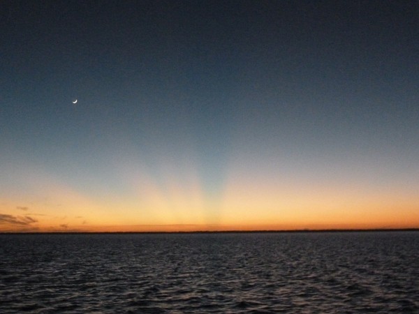 Sunset at Tilloo Cay with sun rays and moon on dusk.  Bahamas.