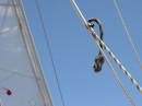 The shroud here is being pulled down by a second rope attached through a pulley to a winch to keep the mast stable. It is attached to the shroud with a jubilee clip and piece of water hose!