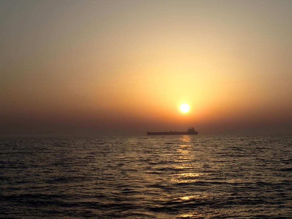 Sunrise at sea over a tanker