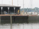 Three empty barges with large wells to receive the sand are lined up in front of the boathouse.