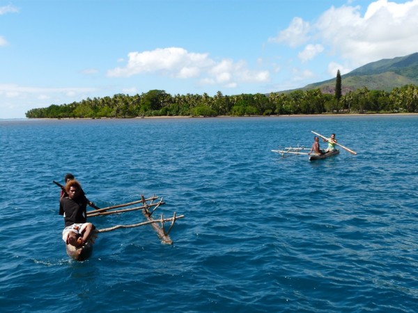 Young men paddle out to invite us to their village within minutes of dropping the hook.