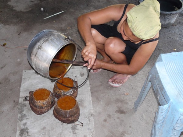 Expertly pouring hot palm sugar into smaller pots