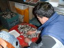 Man filets sardines in the market. A very tedious job