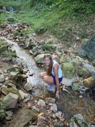 Debby tests the temperature of a creek by the steam vents