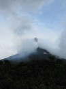 Volcano erupted, dark grey plume visible and rocks spewed