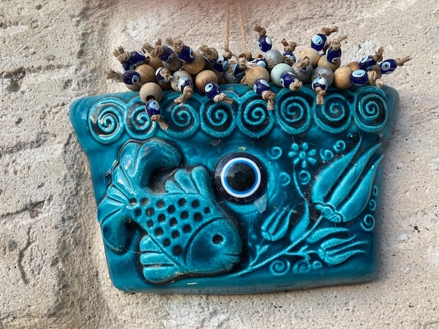 Wall decoration at the Capadocia Caves Hotel.  Notice the “Nazar” or  Turkish Evil Eye.: Evil eyes are often seen around Turkey, built into people’s homes.
It is believed that the “eye” protects its owner from evil spirits and the jealousy and “Ill will of others”.