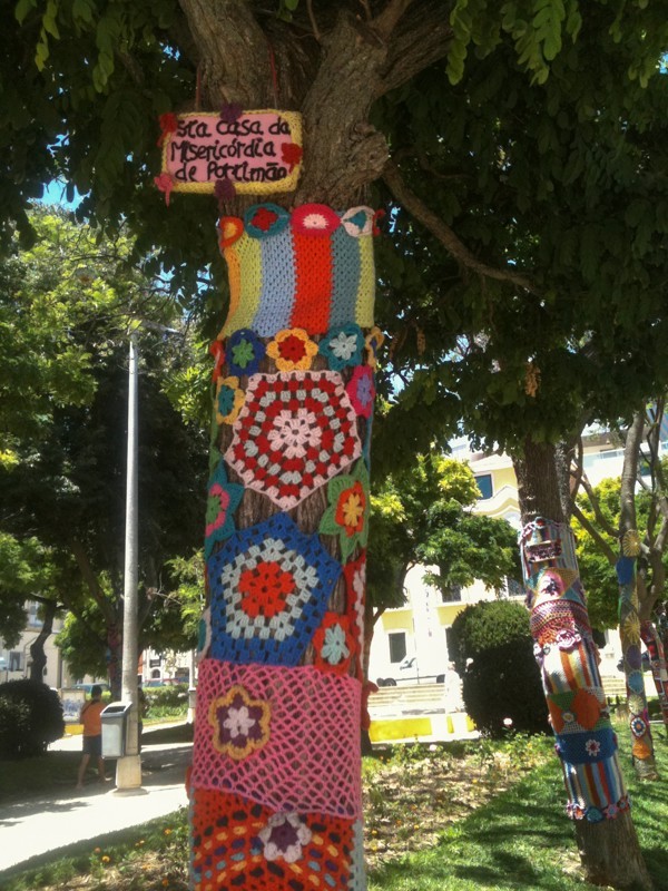 Typical in Portugal and we have seen it in Spain as well.  Trees are dressed in parks or sometimes just on the street.  It is called yarn bombing and is believed to have started in the US and has spread worldwide.  Not sure what the motive is other than to bring color and to personalize areas in the communities.
