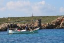 fisherman rowing the traditional fishing boat in Cala Tosquesta, Menorca