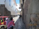 Side street in the historical center of Cusco, with the original Inca stones present as the base of the buildings.  Note the Quechua woman carrying her child.
