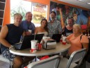 After several days with no internet service, cruisers gather at Carls Jr., Laufou shopping center in Nuuuli, for breakfast and a word with Blue Sky, our internet provider located in the same building. From left: Anatoli (Puppy); Jim (Cactus Wren); Natasha (Puppy); Kimball (Altaira); Don & Judy (Windryder).  We did get some temporary relief a couple of days later.