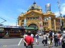 A modern-day streetcar lumbers along in front of the historic Flinders Street Station.