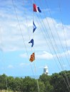 Signal flags fly against a bright blue sky with the lighthouse in the background.