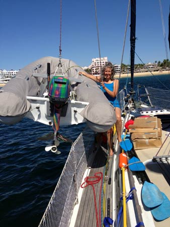 Heidi helping to hoist the dinghy and art-board. This is how we stow the dinghy each night, hanging from a halyard, and chained to a shroud. Thefts aren