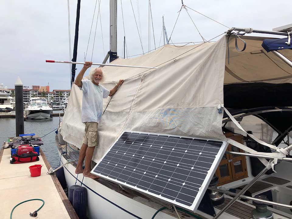 Capitán Kirk cleaning the sun-awning on s/v Due West. The awning also acts as an excellent wind-tunnel, funneling the cooling breezes down through the hatches. 