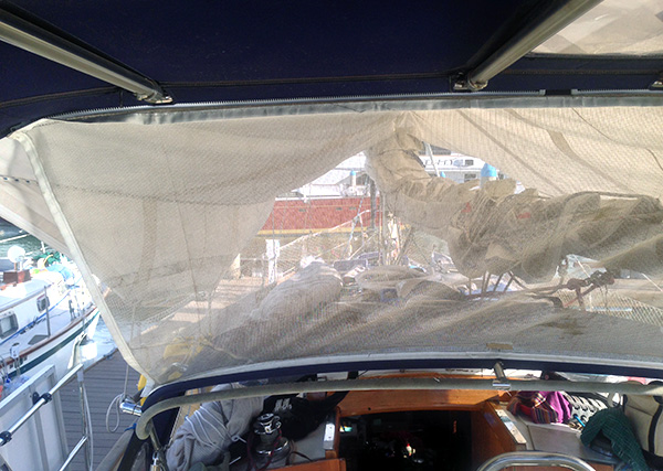 The view from inside the cockpit looking through our mesh Bimini-dodger connector piece, which lets breezes through and dampens the big winds at night.
