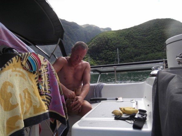 Tom working on opening up a coconut he harvested from a tree.  Anchored in Taioa Bay.